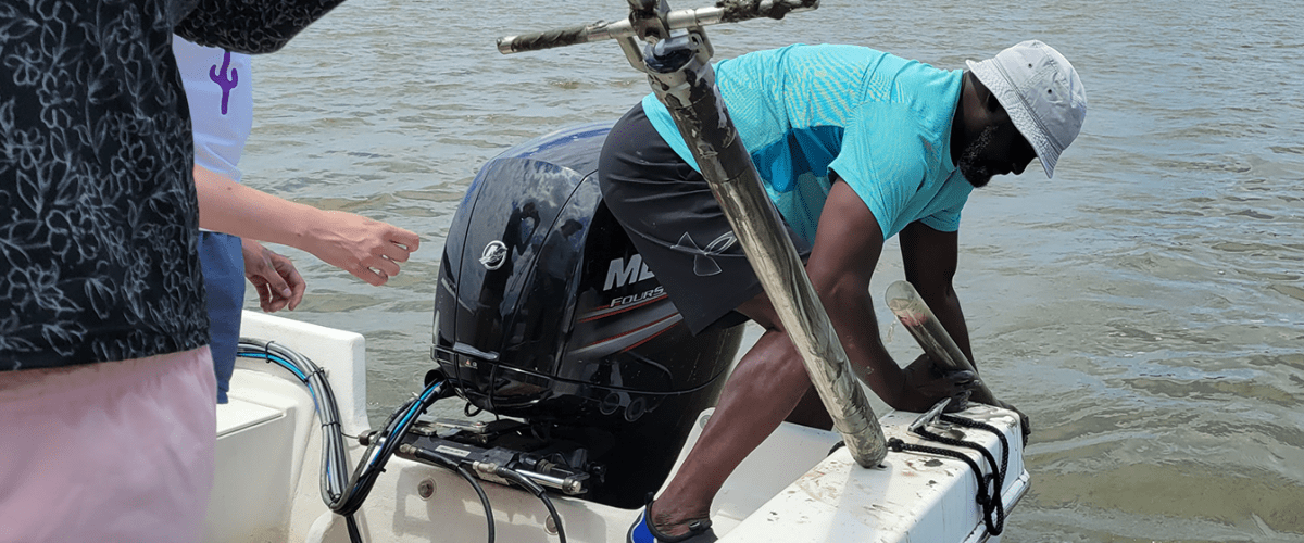 Researcher leaning off boat collecting a water sample