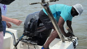 Researcher leaning off boat collecting a water sample