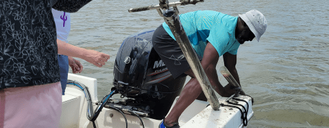 Researcher leaning off boat collecting a water sample